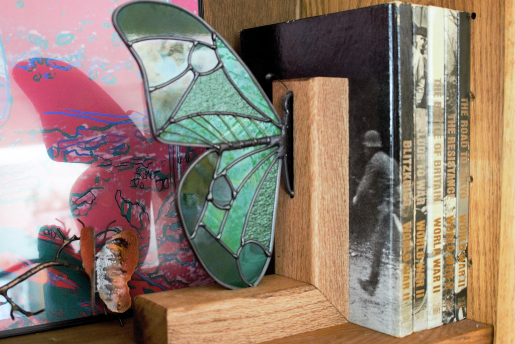 Handmade stained glass butterfly wing bookend in deep green tones, displayed on a shelf
